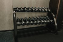 Ensemble d'haltères couché sur rack dans la salle de gym — Photo de stock