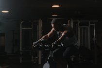 Homme noir sérieux sur vélo d'appartement dans la salle de gym — Photo de stock