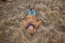 Kid lying on dry grass near creek — Stock Photo