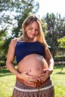 Усміхнена вагітна приваблива жінка в парку — стокове фото
