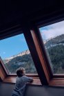 Junge blickt durch Fenster auf den Berg — Stockfoto