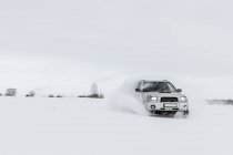 Carro dirigindo no campo de neve — Fotografia de Stock