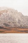 Человек в желтом плаще собирается на берегу озера возле горы в Исобе, Кастилия и Леоне, Испания — стоковое фото