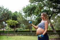 Pregnant attractive woman training with dumbbells — Stock Photo