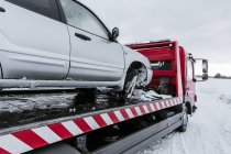 Машина на евакуаторі на сніговій дорозі — стокове фото