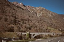 Wonderful view of bridge near asphalt route and dry forest growing on mountain in Canfranc-Station, Huesca, Spain — Stock Photo