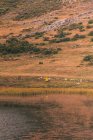Person in yellow raincoat going on shore of lake near wigwam and hill in Isoba, Castile and Leon, Spain — Stock Photo