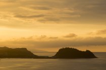 Veduta di scogliere in acque tranquille di mare illuminate con luce dorata del tramonto — Foto stock