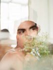Side view of young shirtless guy with fresh white flowers in hands looking away on blurred background — Stock Photo