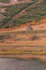 Personne en imperméable jaune sur la rive d'un lac près de Wigwam et colline à Isoba, Castille et Léon, Espagne — Photo de stock