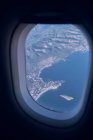 Вид из окна самолета на сушу с горами и морем — стоковое фото