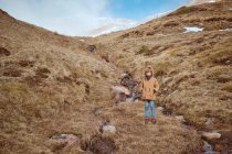 Netter Junge steht auf einem Hügel in Bachnähe — Stockfoto
