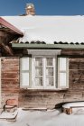 Window of old wooden building in snow in sunny weather in Vilnius, Lithuania — Stock Photo
