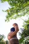 Souriant femme enceinte attrayant dans le parc — Photo de stock