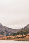Человек в желтом плаще собирается на берегу озера возле вигвам и холма в Исобе, Кастилия и Леон, Испания — стоковое фото