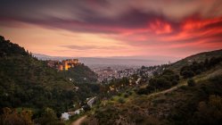 Malerischer Blick auf den schönen Abendhimmel mit dicken Wolken über grünen Hügeln und der Stadt — Stockfoto