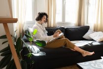 Woman drawing on paper on sofa in room — Stock Photo