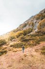 Person with backpack on meadow, cloudy sky and view on mountains with forest in Isoba, Castile and Leon, Spain — Stock Photo