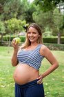Mujer atractiva embarazada con manzana en la estera en el parque - foto de stock
