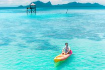 Barca maschile in canoa con pagaia sul mare azzurro sorprendente e cielo blu in Malesia — Foto stock