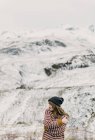 Attraente signorina in maglione e cappello con le mani incrociate vicino collina su sfondo sfocato nei Pirenei — Foto stock