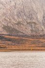 Pessoa de capa de chuva amarela que vai à margem do lago perto de uma montanha em Isoba, Castela e Leão, Espanha — Fotografia de Stock