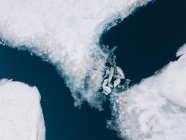 Разбитые ледяные плиты, плавающие в холодной арктической воде около снежного берега, снятые сверху — стоковое фото