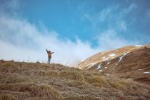 Unerkennbares Kind in warmer Kleidung steht auf einem Hügel vor bewölktem Himmel in der herbstlichen Landschaft — Stockfoto