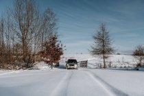Automobile driving between snow meadow near woods and blue sky in Vilnius, Lituânia — Fotografia de Stock