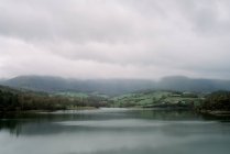 Vue pittoresque sur le lac entre les plantes et les montagnes par temps pluvieux à Oruna, Espagne — Photo de stock