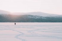 У величній арктичній сільській місцевості люди стоять на білому снігу біля замерзлої річки. — стокове фото