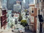 Automobile conduite dans la rue entre les bâtiments et les gratte-ciel dans la journée d'été à San Francisco, États-Unis — Photo de stock