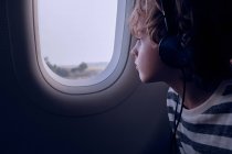 Lindo chico con auriculares en avión - foto de stock
