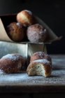 Torta fresca vicino set di pane al forno in carta artigianale con zucchero a velo sul tavolo di legno al buio su sfondo nero — Foto stock