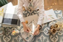 Zugeschnittenes Bild einer Frau am Tisch mit Laptop, Pinseln, Materialien, Bleistiften und Laken im Zimmer — Stockfoto