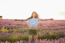 Усміхнена молода жінка співає у великому фіолетовому лавандовому полі — стокове фото