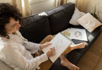 Femme dessin sur papier sur canapé dans la chambre — Photo de stock