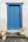White construction with blue door and blooms in pots on stairs in Pyrenees — Stock Photo