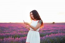 Молода жінка тримає квіти між фіолетовим лавандовим полем — стокове фото