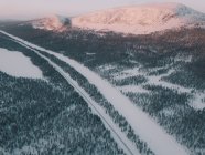 Чудовий безпілотний вид вузької дороги, що проходить через дивовижну арктичну сільську місцевість біля величної сніжної гори. — стокове фото
