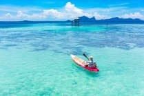 Vue de dos bateau mâle en canot avec pagaie sur la mer azur incroyable et ciel bleu en Malaisie — Photo de stock