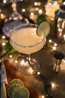 Склянка коктейлю маргарита на столі з інгредієнтами та вогнями — стокове фото
