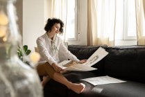 Woman drawing on papers on sofa in room — Stock Photo