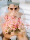 Doppelbelichtung eines brünetten jungen Mannes und eines Straußes frischer Blumen, die auf verschwommenem Hintergrund in die Kamera schauen — Stockfoto