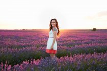 Woman standing between big violet lavender field at sunset — Stock Photo