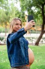 Donna attraente incinta utilizzando il telefono cellulare — Foto stock