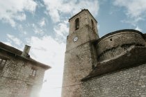 Desde debajo de la torre cerca de la construcción de ladrillos y el cielo azul en las nubes en los Pirineos - foto de stock