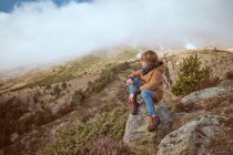 Menino sentado perto da colina no dia nebuloso — Fotografia de Stock