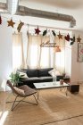 Композиция светлой комнаты с диваном, стулом, столом на ковре и рождественскими украшениями — стоковое фото