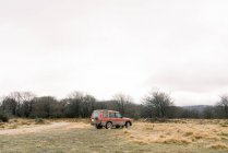 Off roader parked on meadow with dry grass near bushes and cloudy sky in Orduna, Spain — Foto stock